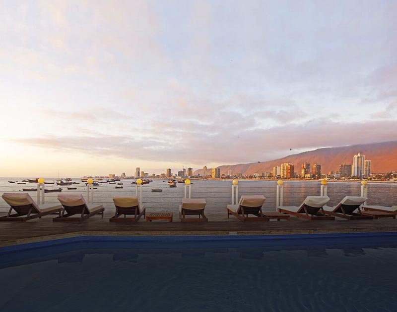 Chairs next to a pool at the Hotel Terrado Suites, overlooking the ocean and the Iquique skyline.